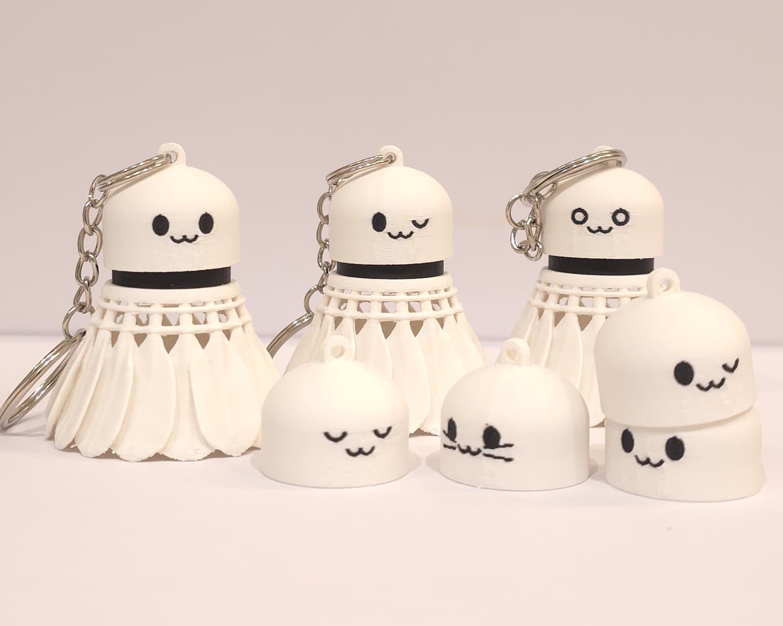 Three white badminton shuttlecock clickers with different faces, and three spare corks in front showing more faces