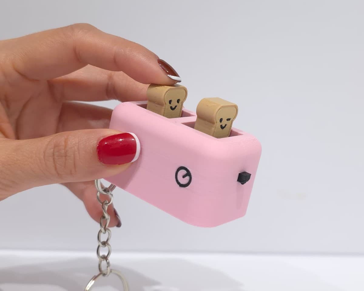 A hand pressing a slice of toast down into the pink toaster clicker